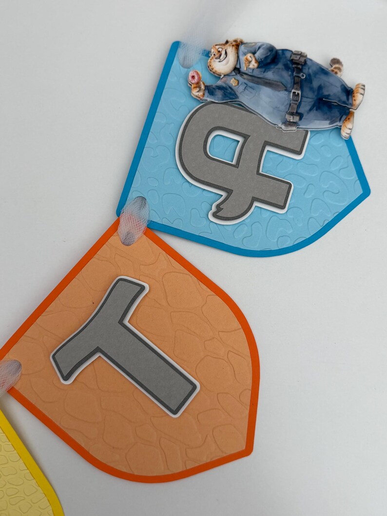 May include: A decorative banner featuring two shield-shaped pennants. The top blue pennant displays a grey letter H and a cartoon cheetah police officer holding a donut. The bottom orange pennant features a grey letter T with a textured surface.