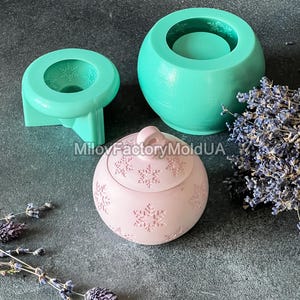 Pu&ograve; includere: Tre stampi in silicone per la realizzazione di candele. Gli stampi sono verdi e rosa. Lo stampo rosa ha la forma di un ornamento natalizio e presenta un motivo a fiocco di neve. Gli stampi verdi sono rotondi e hanno un bordo rialzato intorno alla parte superiore.