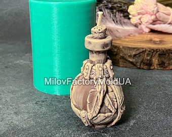 Pode incluir: Uma forma de silicone verde para fazer uma vela em forma de garrafa marrom com um design detalhado de folhas e uma superfície texturizada. A forma é cilíndrica e tem um furo na parte superior para despejar a cera.