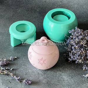Pu&ograve; includere: Tre stampi in silicone per la realizzazione di candele. Gli stampi hanno la forma di un barattolo rotondo, un piccolo barattolo rotondo e un ornamento natalizio. Lo stampo dell'ornamento ha un motivo a fiocco di neve. Gli stampi sono verdi e rosa.