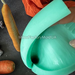 May include: A close-up of a light teal silicone mold, shaped like a carrot. A realistic carrot and a piece of orange fabric are also visible. The text "MilovFactoryMoldUA" is printed on the image.