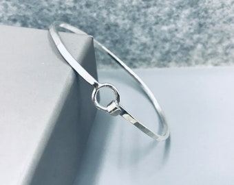 Oval silver bangle with O clip opening
