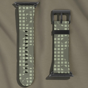 Könnte beinhalten: Zweiteiliges Uhrenarmband mit einem Tarnmuster in Grün- und Beigetönen. Das Armband hat ein gitterartiges Design mit dunkleren Formen. Die Schnalle und die Anschlüsse sind schwarz.