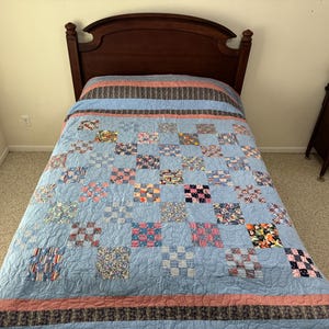 May include: A blue and red patchwork quilt with a floral pattern on a wooden bed frame.