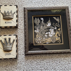 May include: Decorative wall art set featuring a framed Asian-inspired print and two crown plaques. The framed print has a black background with gold and white figures. The plaques read "KING" and "QUEEN" with silver crowns.