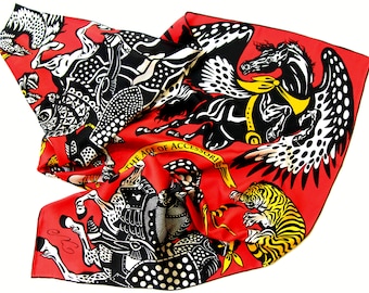 Puede incluir: Un pañuelo de seda rojo con una ilustración en blanco y negro de criaturas míticas, incluyendo caballos alados y un tigre. El pañuelo tiene un borde negro y el texto "THE AGE OF ACCESSORI" en dorado.