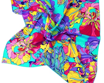 Puede incluir: Un pañuelo cuadrado de seda con un vibrante estampado floral. El diseño presenta grandes flores estilizadas en tonos de rojo, rosa, amarillo, morado y azul sobre un fondo turquesa. El pañuelo está doblado, mostrando los intrincados detalles de la obra.