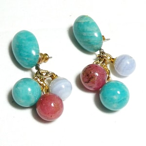 May include: A pair of dangle earrings featuring turquoise and pink stones. The earrings have a gold chain with multiple turquoise and pink beads.
