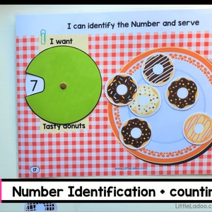 May include: A colorful educational game for kids featuring a plate of donuts and a spinner with the number 7. The game is designed to help children learn number identification and counting. The text on the game board reads "I can identify the Number and serve" and "I want Tasty donuts".