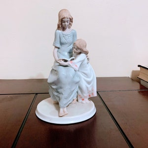Hand crafted Meico Inc. Mother and daughter reading a book. Pastel blue, white, pink and gray statue, 8” Tx 4 3/4” in diameter