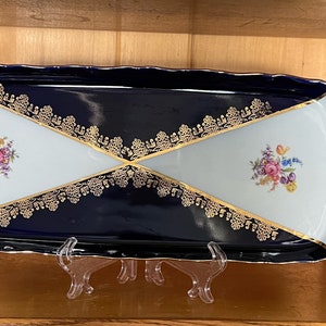 Könnte beinhalten: Ein kobaltblaues und weißes Porzellanserviertablett mit goldenen Verzierungen und Blumendesigns. Das Tablett hat einen gewellten Rand und ist in zwei Abschnitte unterteilt.