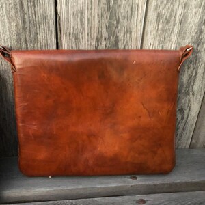 Peut inclure: Un sac messager en cuir brun avec une fermeture &agrave; rabat et une bandouli&egrave;re. Le sac est fait de cuir souple et doux et a un aspect vintage.