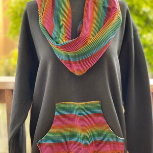May include: Black sweatshirt with a rainbow striped pocket and a matching rainbow striped scarf.