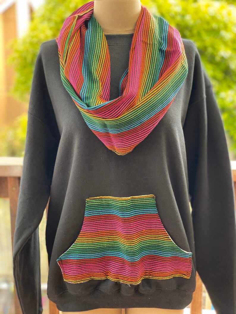May include: Black sweatshirt with a rainbow striped pocket and a matching rainbow striped scarf.