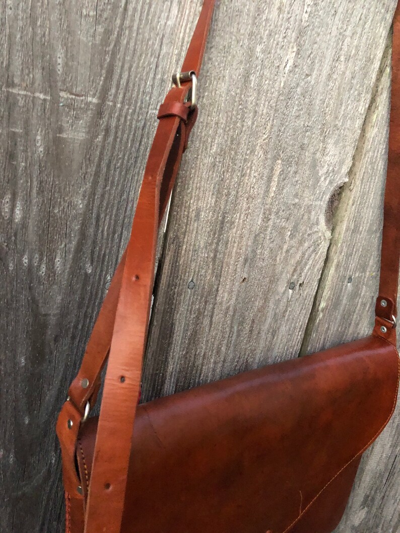 Peut inclure: Un sac &agrave; main en cuir marron avec une longue bandouli&egrave;re r&eacute;glable. Le sac a une fermeture &agrave; rabat et une boucle argent&eacute;e.