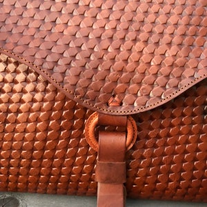 Peut inclure: Un sac en cuir brun avec un motif tiss&eacute; et une sangle en cuir avec un anneau m&eacute;tallique.
