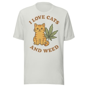 Camiseta divertida de gato con marihuana. Me encantan los gatos y la marihuana. Estilo vintage de dibujos animados, colores descoloridos y desgastados. Camiseta para fumetas con diseño de hoja de cannabis.