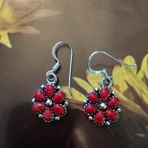 May include: A pair of silver dangle earrings with red coral flower accents.