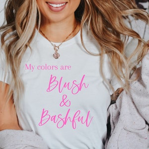 May include: White t-shirt with the text "My colours are Blush & Bashful" printed in pink.