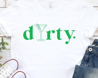 Może przedstawiać: Biała koszulka z zielonym napisem "dirty" i zielonym grafiką kieliszka do martini.