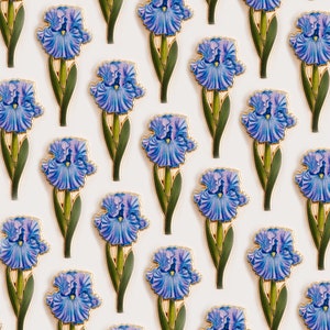 May include: A white background with a repeating pattern of blue and purple iris flowers with gold accents. The flowers are arranged in a grid pattern.