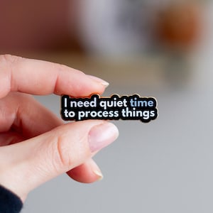 May include: Black enamel pin with gold trim that reads "I need quiet time to process things".