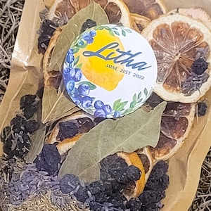 May include: A brown paper bag filled with dried lemon slices, bay leaves, blueberries, and lavender. The bag has a sticker on it that says "Lithe June 21st 2022".