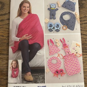May include: A Simplicity sewing pattern featuring a woman wearing a pink wrap. The pattern includes instructions for making baby items like a bib, booties, and a toy. The pattern number is 8312.