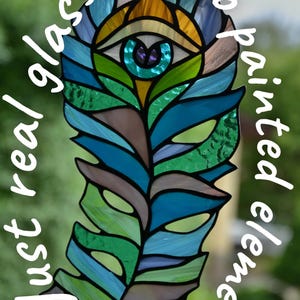 May include: A stained glass peacock feather design with an eye at the top, featuring shades of blue, green, and brown. The text reads "Just real glass" and "No painted elements". The Glass G Studio logo is at the bottom.