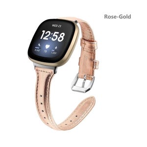 May include: Rose-gold leather watch band for a smartwatch with a square face. The watch face displays the time, date, heart rate, and steps taken. The band has a buckle closure.