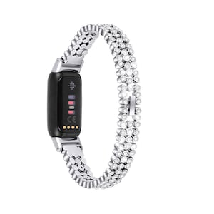 Può includere: Un braccialetto per orologio in metallo argentato con una fila di piccoli strass. Il braccialetto è progettato per uno smartwatch con uno schermo nero.