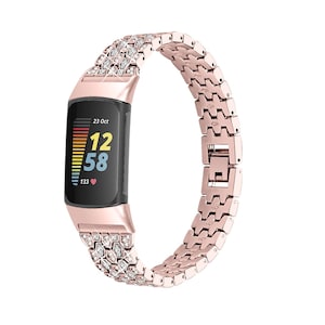Op de afbeelding: Roze gouden metalen horlogeband met een met kristallen bezet ontwerp. De band is compatibel met een fitness tracker met een digitaal display dat de datum, tijd en hartslag weergeeft.