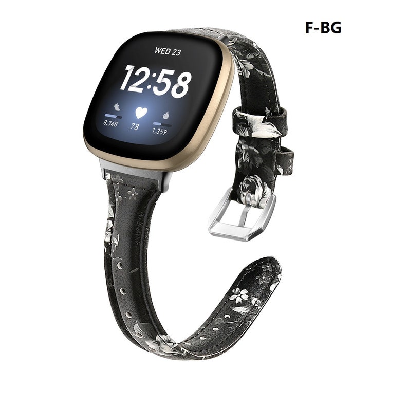May include: Black and white floral patterned leather watch band for a smartwatch. The band has a silver buckle and is compatible with Fitbit Sense and Versa smartwatches.