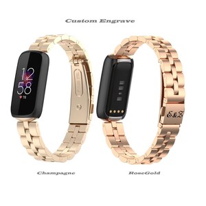 May include: Two smart watch bands in champagne and rose gold. The champagne band displays a digital clock with the time 12:58 and a heart rate of 78. The rose gold band is engraved with the initials E&Z. The text "Custom Engrave" is above the bands.