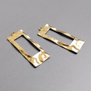 May include: Two gold-colored metal rectangular frames with a textured surface. The frames have a slightly wavy edge and a smooth interior.