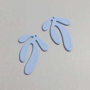 May include: Two light blue abstract shapes with a hole in the top. The shapes are reminiscent of leaves or branches.