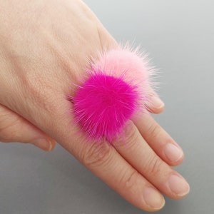Op de afbeelding: Een roze en fuchsia nep bont ring met twee pluche pompoenen.