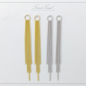May include: Gold and silver chain tassel earrings. Each earring has a small circular loop at the top, connected to multiple strands of delicate chains. The earrings are displayed on a white background, with the text "Trond Tassel" at the top.