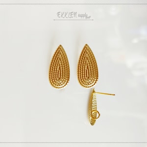 May include: A pair of gold teardrop-shaped earrings with a textured design. The earrings have a post and a small loop for attaching to an earring hook.
