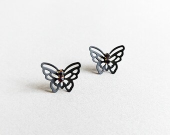 May include: A pair of black butterfly earrings with small, dark red rhinestones in the center of each butterfly.