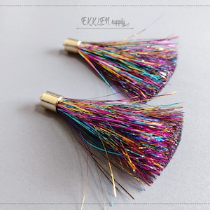 May include: Two colourful metallic tassel trims with gold-coloured metal caps. The tassels are made of iridescent, multi-coloured fibres.