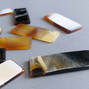 Puede incluir: Surtido de piezas de joyer&iacute;a de cuerno de forma rectangular en varios tonos de marr&oacute;n, negro y blanco.