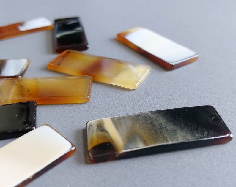 Puede incluir: Surtido de piezas de joyer&iacute;a de cuerno de forma rectangular en varios tonos de marr&oacute;n, negro y blanco.