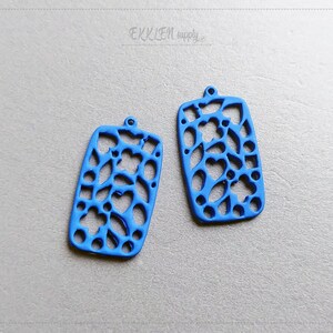 May include: Two blue metal rectangular earring blanks with a delicate floral cutout design.