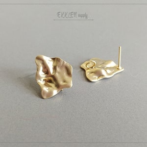 May include: A pair of gold-toned earrings with a textured, irregular shape. The earrings have a post and a loop for attaching to an earring back.