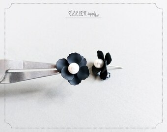 May include: A pair of black flower-shaped earrings with a white pearl in the center of each flower.