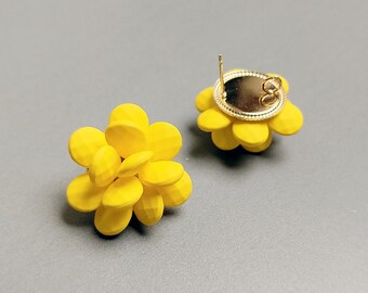 May include: A pair of yellow flower-shaped earrings. The earrings are made of small, round, yellow beads that are clustered together to form a flower shape. The earrings have a gold-colored backing.