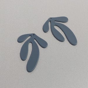May include: Two dark blue abstract shapes with a hole at the top. The shapes are similar but slightly different in size and form.