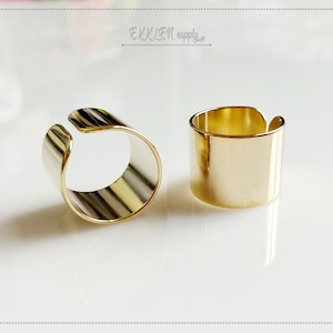 Puede incluir: Dos anillos de metal de color dorado, uno con una banda ligeramente más ancha que el otro. Ambos anillos están abiertos por un lado, lo que permite que se usen en un dedo.