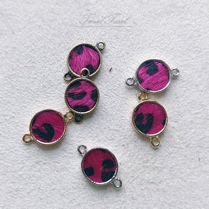 May include: Five gold and silver tone metal connector charms with pink and black leopard print fabric inserts. The charms have two jump rings for attaching to jewelry.